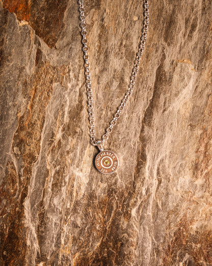 A necklace with a round olive green pendant on a 925 sterling silver chain, displayed on a wooden surface.