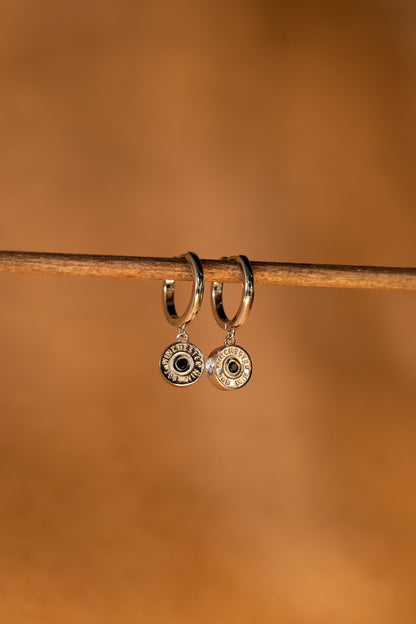 Silver hoop earrings on a rustic wire fence